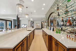 Kitchen with wood finish cabinets, light stone counters, hanging light fixtures, and open floor plan