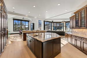 Kitchen featuring light stone counters, dark wood finish cabinetry, light wood-type flooring, backsplash, and recessed lighting