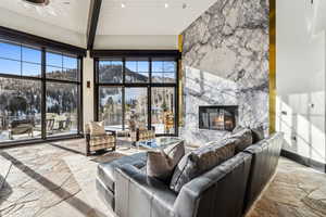 Living room with stone flooring, a high end fireplace, healthy amount of natural light, and a high ceiling