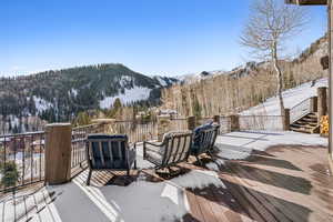 Snow covered deck with a mountain view and a wooded view