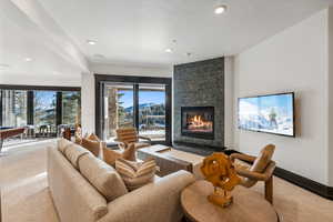Living room featuring a stone fireplace, light carpet, pool table, and recessed lighting