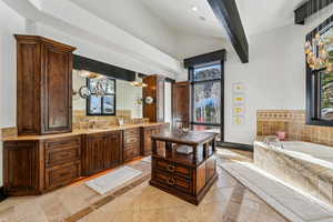 Bathroom featuring vanity, a bath, vaulted ceiling, and backsplash