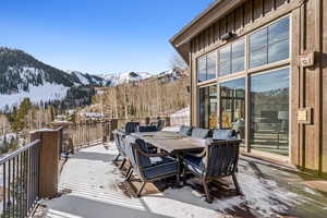 Snow covered deck with a mountain view and outdoor dining space