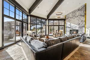 Living room featuring a premium fireplace, stone finish floors, hanging lights, and vaulted ceiling