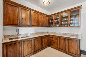 Kitchen featuring glass insert cabinets, wood finish cabinets, and light stone countertops