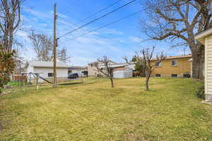 Fenced yard featuring a trampoline and a playground