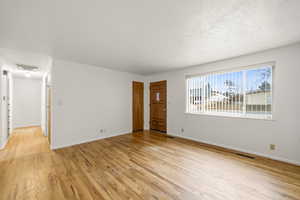 Unfurnished living room with light wood finished floors and a textured ceiling