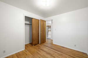 Unfurnished bedroom featuring light wood finished floors, a closet, and freestanding refrigerator