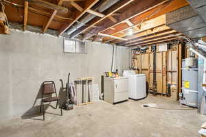 Unfinished below grade area featuring washer and clothes dryer and secured water heater