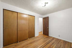 Unfurnished bedroom featuring light wood-style flooring, a textured ceiling, and a closet
