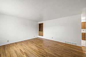 Spare room with a textured ceiling, light wood finished floors, and built in shelves