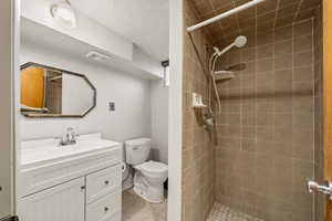 Bathroom with vanity, a textured ceiling, a shower stall, and light tile patterned floors