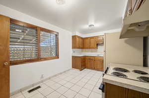 Kitchen with wood finish cabinets, light countertops, light tile patterned floors, and backsplash