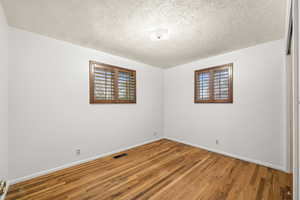 Unfurnished room featuring wood finished floors and a textured ceiling
