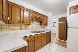 Kitchen with wood finish cabinets, freestanding refrigerator, light countertops, and light tile patterned floors