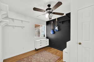 Walk in closet with light wood-style flooring and ceiling fan
