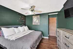 Bedroom with dark wood finished floors, ceiling fan, and a textured ceiling