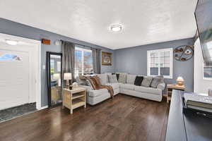 Living room featuring dark wood-style floors and a textured ceiling