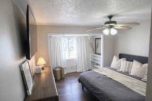 Bedroom with dark wood-style floors, ceiling fan, and a textured ceiling