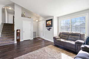 Living room featuring lofted ceiling and dark wood-style floors