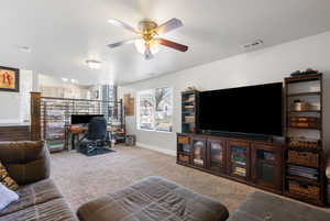 Living room with carpet flooring, a desk, and ceiling fan
