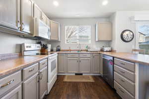 Kitchen featuring stainless steel appliances, a peninsula, recessed lighting, dark wood-style floors, and gray cabinetry