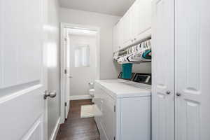 Laundry area with dark wood-style flooring, cabinet space, and separate washer and dryer