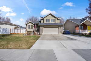 View of front of property with driveway, a garage, stone siding, and stucco siding