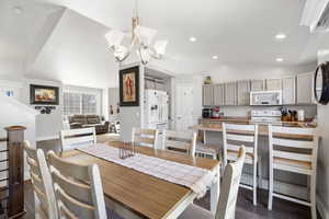 Dining room with lofted ceiling, dark wood finished floors, and a chandelier