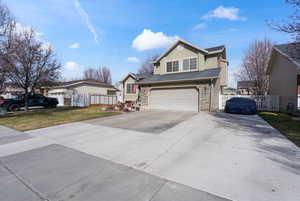 Traditional-style home with driveway, an attached garage, stone siding, and stucco siding