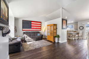 Living area with vaulted ceiling, LVP dark wood finished floors, and recessed lighting