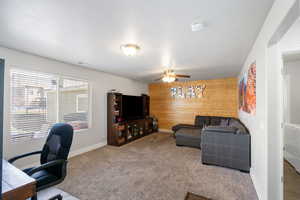 Office space with wood walls, carpet, a ceiling fan, and an accent wall
