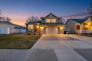 Traditional-style house featuring concrete driveway, a garage, a porch, and stone siding