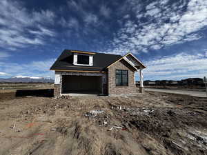 Unfinished property featuring brick siding, a garage, a shingled roof, and a mountain view