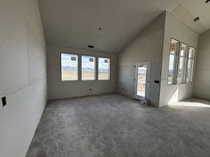 Unfurnished room featuring concrete floors and vaulted ceiling
