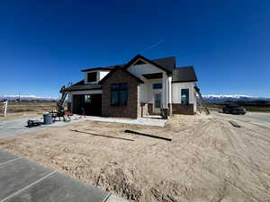 Modern inspired farmhouse featuring a mountain view, brick siding, board and batten siding, a shingled roof, and covered porch