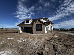 Property under construction featuring brick siding, a garage, a shingled roof, and a mountain view
