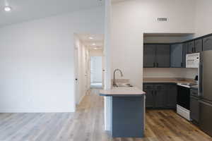 Kitchen with light countertops, range with electric stovetop, freestanding refrigerator, a peninsula, and recessed lighting
