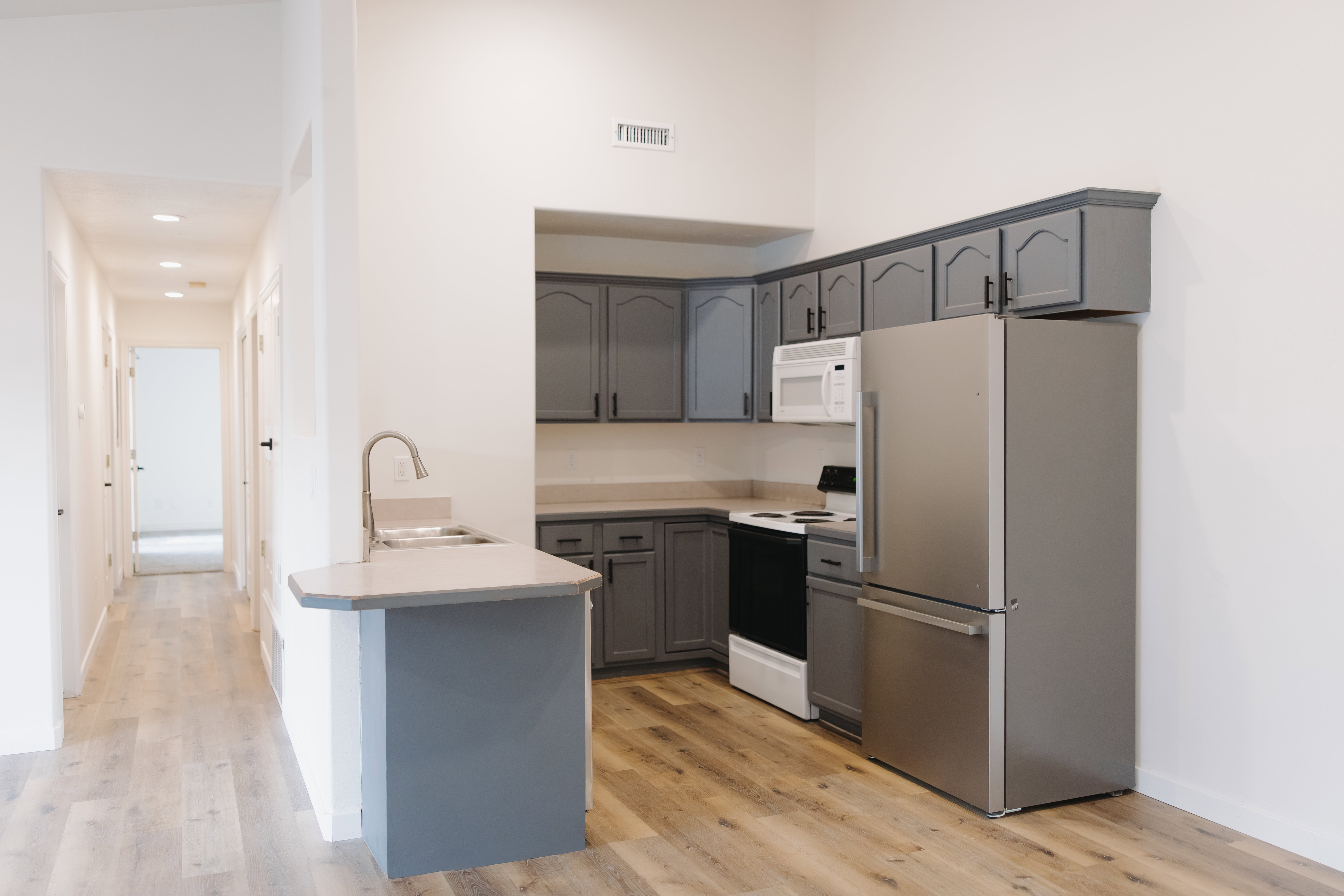 Kitchen with white appliances, gray cabinets, light countertops, a peninsula, and recessed lighting