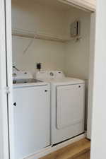 Laundry area with washing machine and dryer and light wood finished floors