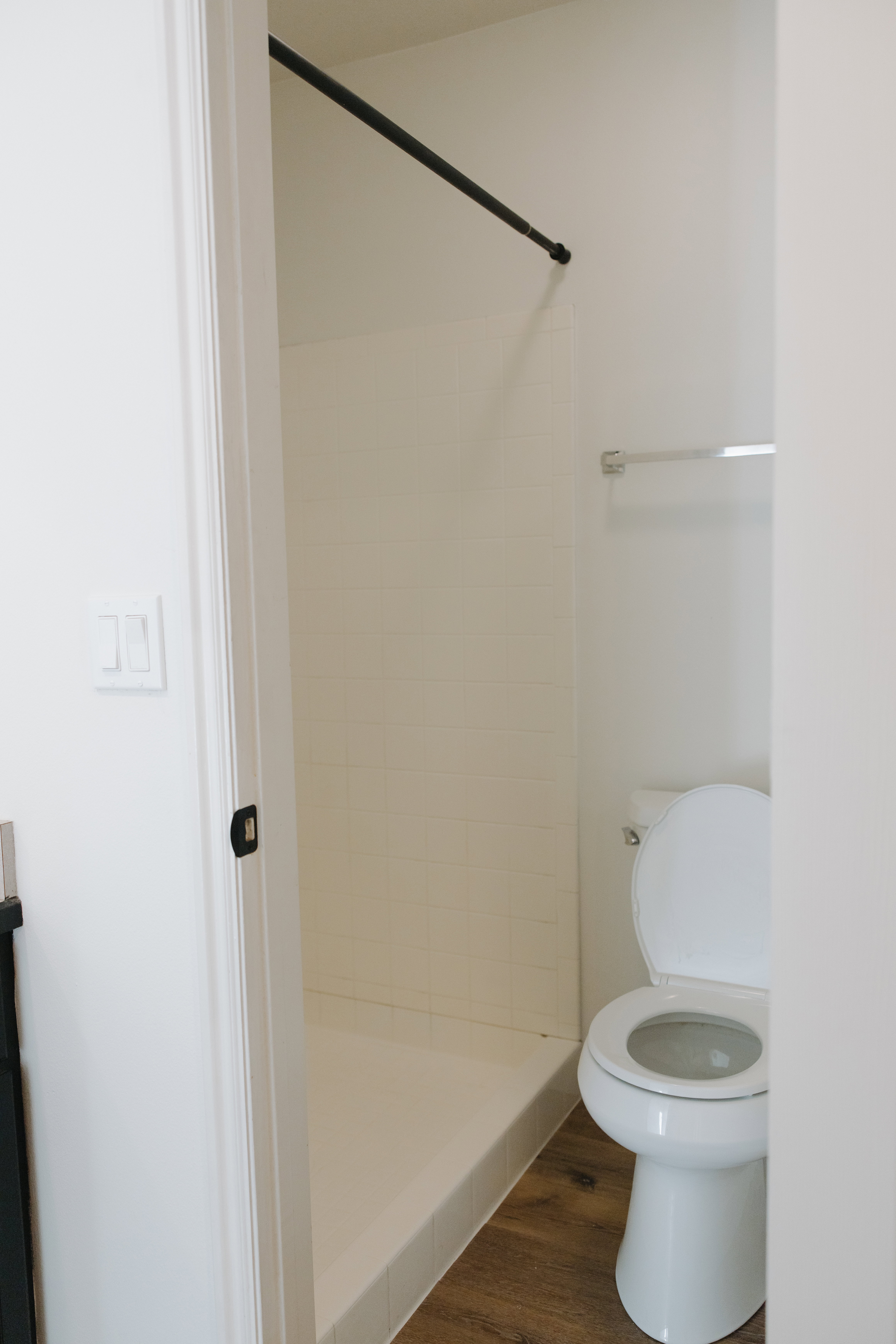 Bathroom featuring a shower stall and dark wood-style floors