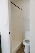 Bathroom featuring a shower stall and dark wood-style floors