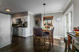 Dining space with ornamental molding, dark wood-style flooring, and a textured ceiling