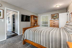 Bedroom with dark carpet, a textured ceiling, and crown molding