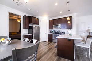 Kitchen featuring dark wood finish cabinets, a kitchen bar, stainless steel appliances, a peninsula, and a textured ceiling