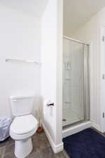 Full bath featuring a stall shower and toilet