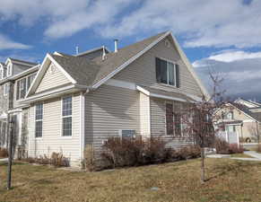 View of side of home featuring roof with shingles and a lawn