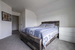 Carpeted bedroom with lofted ceiling and baseboards