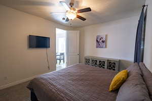 Bedroom featuring a textured ceiling, carpet flooring, and a ceiling fan