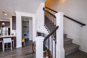Stairs featuring crown molding, washer / dryer, wood finished floors, and a textured ceiling